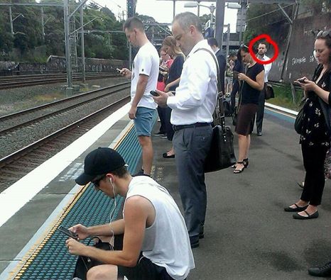 Un homme surpris en train de regarder le monde réel sur le quai d'une gare